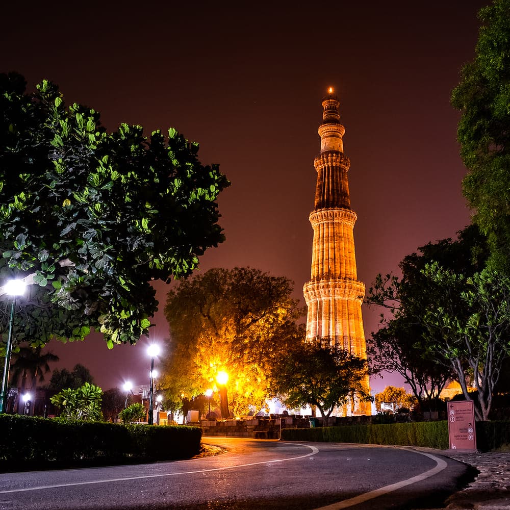 Qutub Minar tower against blue sky with carved sandstone storeys